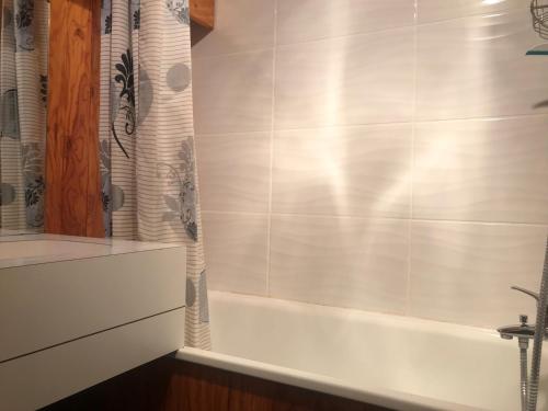 La salle de bains est pourvue d'une baignoire et d'un rideau de douche. dans l'établissement Studio divisé avec terrasse sud, proche pistes et centre station, rez-de-chaussée - FR-1-181-2523, à La Plagne Tarentaise