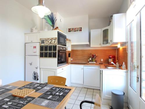 une cuisine avec des armoires blanches et une table dans l'établissement Appartement T3 avec terrasse, proche centre et thermes de La Bourboule - FR-1-608-236, à La Bourboule