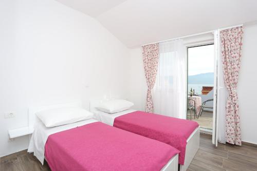 two beds in a white room with a balcony at Seaside family friendly house with a swimming pool Slatine, Ciovo - 17231 in Slatine