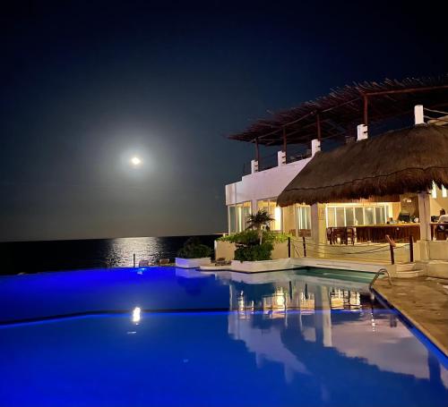 a swimming pool at night with the moon in the background at BOF Apartments Cancun in Cancún