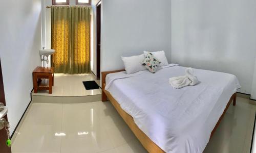 ein Schlafzimmer mit einem großen weißen Bett und einem Fenster in der Unterkunft Santiago Bed and Breakfast at Desa Wisata Moni in Kelimutu