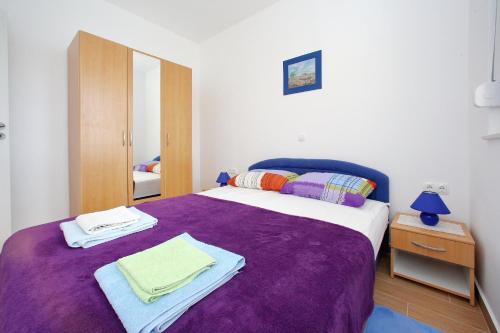 een slaapkamer met een paars bed met handdoeken erop bij Apartments by the sea Bibinje, Zadar - 17269 in Bibinje