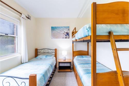 two bunk beds in a small room with a window at Sunnie Belle, 2,3 Victoria Parade - Unit with water views and air conditioning in Nelson Bay