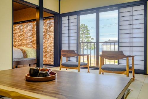 a room with a bed and two chairs and a table at Hamabe no Yado Asahiya in Himi