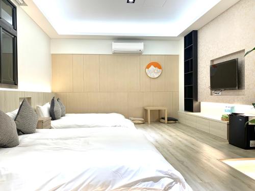 a bedroom with two beds and a flat screen tv at Jabez Homestay in Yilan City