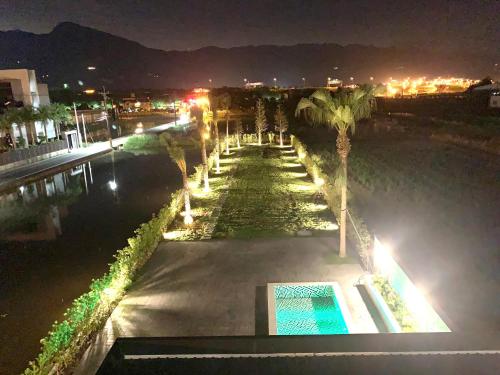 a night view of a pool with palm trees and lights at Jabez Homestay in Yilan City