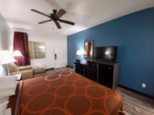 a hotel room with a bed and a couch and a ceiling fan at Super 8 by Wyndham Forney/East Dallas in Forney