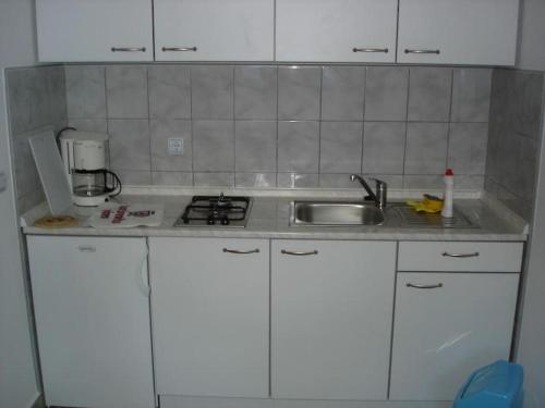 a kitchen with white cabinets and a sink at Apartments by the sea Prizna, Senj - 17309 in Senj