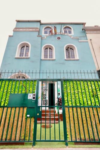 a blue house with a green fence in front of it at The Secret Garden Hostel in Lima