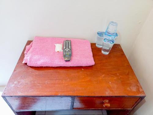 a table with a remote control and two bottles of water at Hotel Gerung 2 near Luwes Mall Nganjuk Mitra RedDoorz in Nganjuk