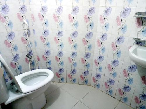a bathroom with a toilet and flowers on the wall at Shopnonir Hotel & Restaurant in Chittagong