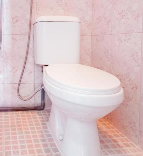 a white toilet in a bathroom with pink tiles at Hotel Gerung 2 near Luwes Mall Nganjuk Mitra RedDoorz in Nganjuk