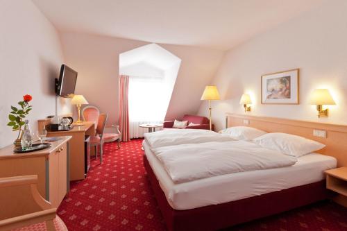 a hotel room with a large bed and a desk at Hotel Für Dich in Waren