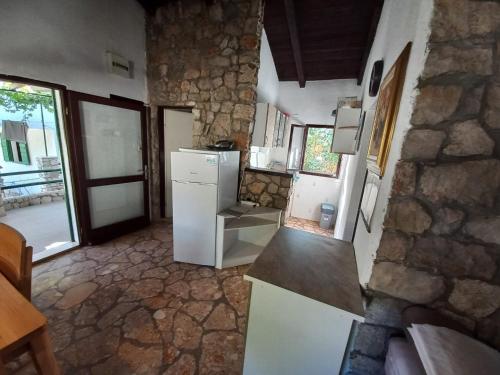 a kitchen with a white refrigerator and a stone wall at Holiday home Ivica - by the sea in Sevid