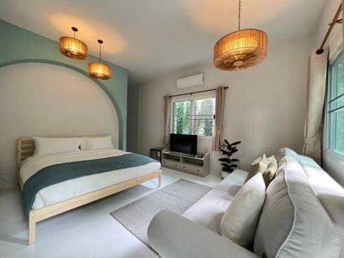 華欣的住宿－Warm White Hua Hin House，一间卧室配有一张床、一张沙发和一台电视。