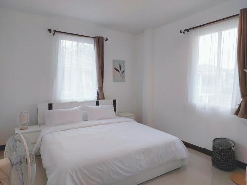 biała sypialnia z białym łóżkiem i 2 oknami w obiekcie HAPPY SPACE วิลล่าทั้งหลัง 2นอน 2น้ำ ฟรี Wifi จอดรถ w mieście Nakhon Phanom