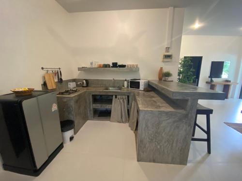 a large kitchen with a counter and a refrigerator at Chalisa Villas Koh Tao in Koh Tao