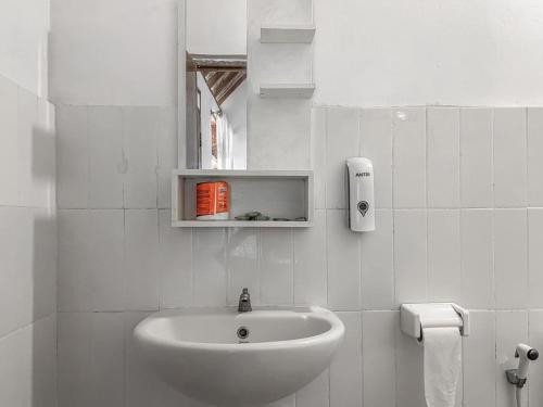 a white bathroom with a sink and a toilet at Aira Homestay near Pantai Kuta Mandalika Mitra RedDoorz in Bumbang