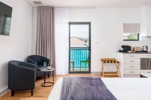a hotel room with a bed and a kitchen with a balcony at Hunter Studios - Maitland in Maitland