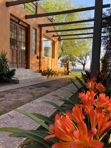 ein Haus mit orangefarbenen Blumen davor in der Unterkunft Casa Chalet "La Roja" -vista a la laguna!!!- in Chascomús