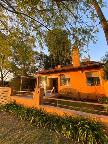 Casa Chalet "La Roja" -vista a la laguna!!!- في شاسكوموس: منزل برتقالي مع شرفة وسياج