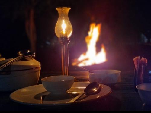 a table with a plate and bowls and a lamp at Ranakpur Nature Retreat in Sādri