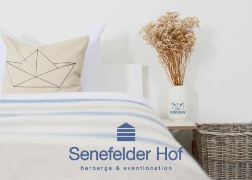 a bed with a paper boat pillow and a vase of flowers at Senefelder Hof in Solnhofen