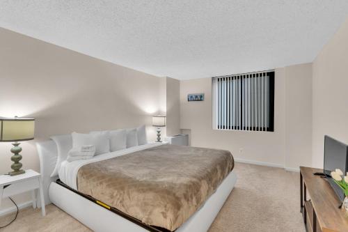 a white bedroom with a large bed and a window at Arlington Fully Furnished Apartments in Crystal City in Arlington