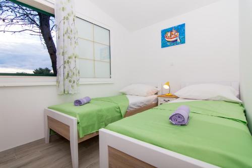 two beds in a room with a window at Secluded fisherman's cottage Cove Duga, Ciovo - 17349 in Okrug Gornji