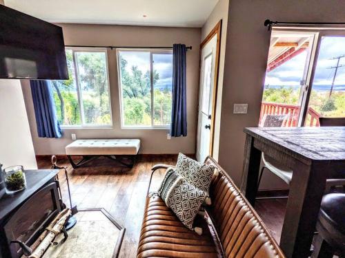 a living room with a couch and a table and windows at The Luminous Lodge-Remodeled Cabin W/ Valley Views in Santa Ysabel