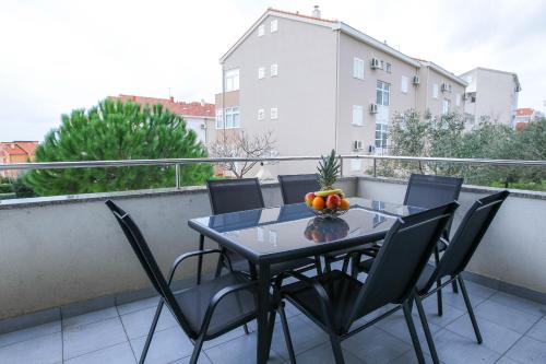un balcón con mesa y sillas y un bol de fruta en Apartments with a parking space Novalja, Pag - 17364, en Novalja