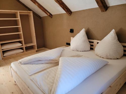 1 dormitorio con 2 camas y almohadas blancas en hoamisch en Malles Venosta
