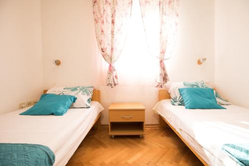 two twin beds in a room with a window at Apartments by the sea Petrcane, Zadar - 17179 in Petrcane