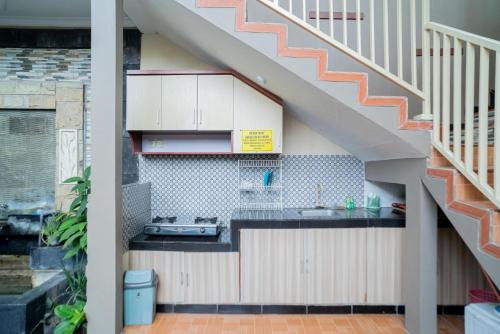 eine Küche unter der Treppe mit einer Theke und einem Waschbecken in der Unterkunft RedDoorz At Villa Akbar 3 in Batu