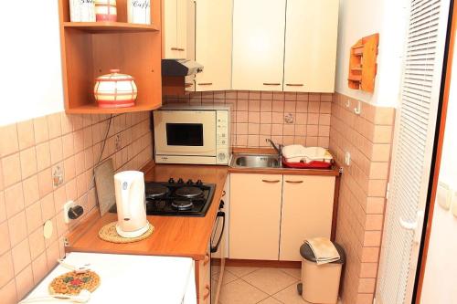 a small kitchen with a stove and a microwave at Apartments by the sea Moscenicka Draga, Opatija - 17381 in Mošćenička Draga