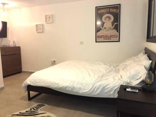 Dormitorio con cama y póster en la pared en יחידה מושלמת ברמת ישי לזוג או יחיד, en Ramat Yishay