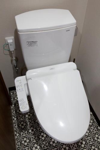 a white toilet in a bathroom with a remote control at TOMMY CONDOMINIUM WAKASA 202 in Kume