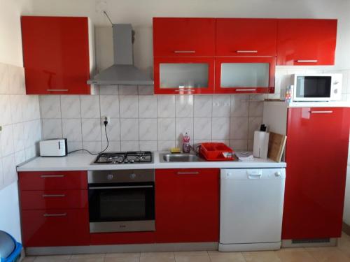 kuchnia z czerwonymi szafkami i piekarnikiem w obiekcie Apartments with a parking space Zadar - 17409 w mieście Zadar