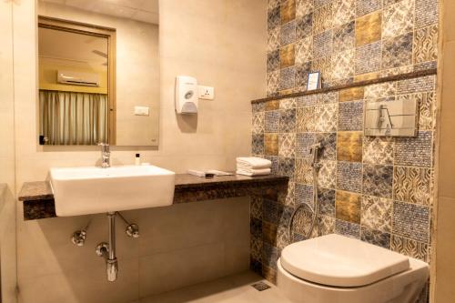 a bathroom with a sink and a toilet and a mirror at Starlit Suites Tirupati in Tirupati