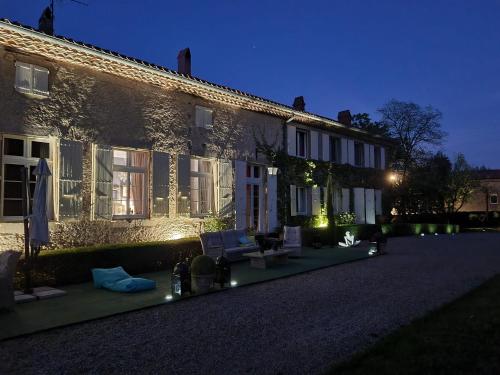 a house with lights on the side of it at night at La Chapelle aux Acacias in Caucalières