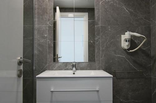 La salle de bains est pourvue d'un lavabo blanc et d'un miroir. dans l'établissement Phaedrus Living: Luxury Suite Nicosia 506, à Nicosie