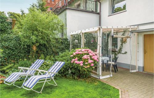 two chairs and a table in a yard with flowers at 2 Bedroom Lovely Apartment In Darlowo in Darłowo