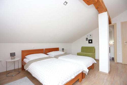 a bedroom with two beds and a green chair at Apartments and rooms with parking space Donje Taboriste, Plitvice - 17486 in Slunj