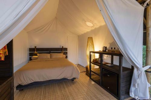 een slaapkamer met een bed in een tent bij Sanda Plantation Hideaway in Sanda