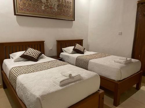 two beds in a hotel room withskirts at Arsa Wayan Guest House in Klungkung
