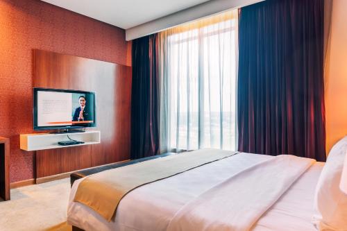 a bedroom with a large bed and a television at Swiss-Belinn SKA Pekanbaru in Pekanbaru