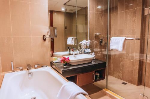 a bathroom with a tub and a sink and a shower at Swiss-Belinn SKA Pekanbaru in Pekanbaru