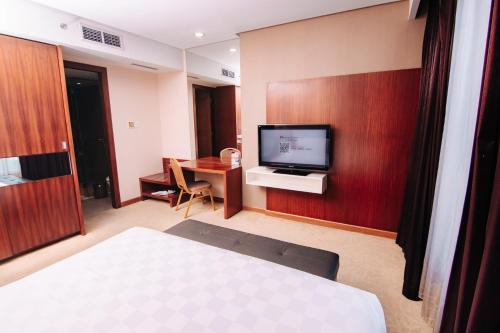 Habitación de hotel con cama y TV en la pared en Swiss-Belinn SKA Pekanbaru en Pekanbaru