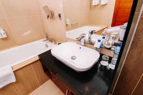 a bathroom with a white sink and a bath tub at Swiss-Belinn SKA Pekanbaru in Pekanbaru
