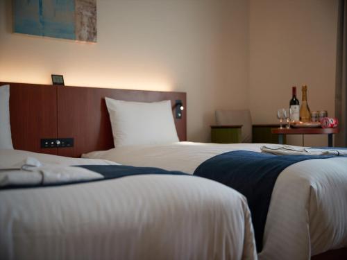 two beds in a hotel room with wine glasses at THE GRAND HOTEL GINOWAN in Ginowan